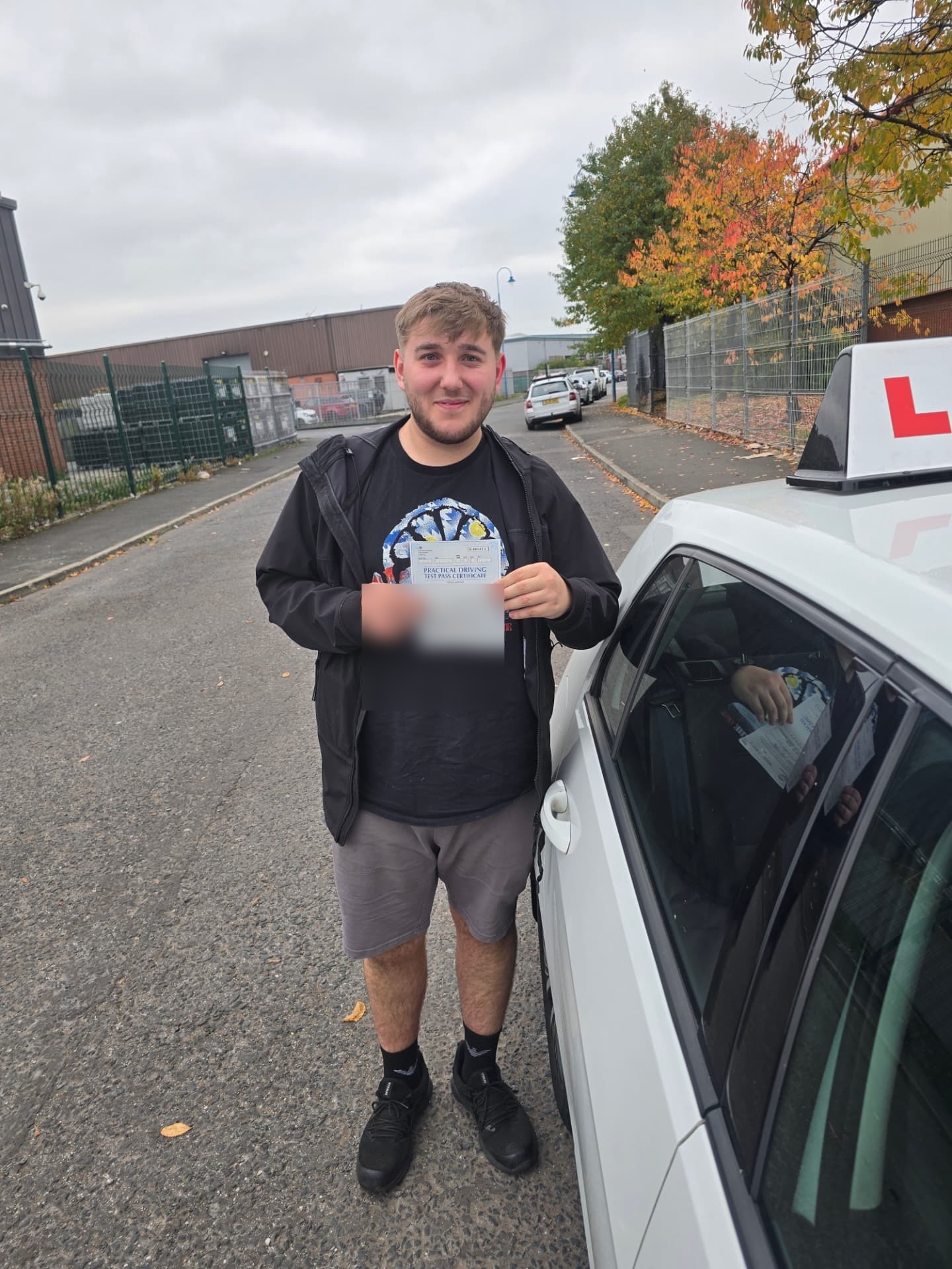 FSK Driving Instructors learner Davis holding his practical driving test pass certificate next to the learner car in Rochdale