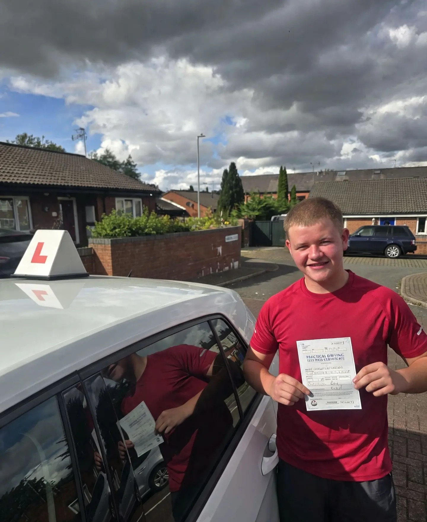 FSK Driving Instructors learner Charlie holding his practical driving test pass certificate next to the learner car in Bury