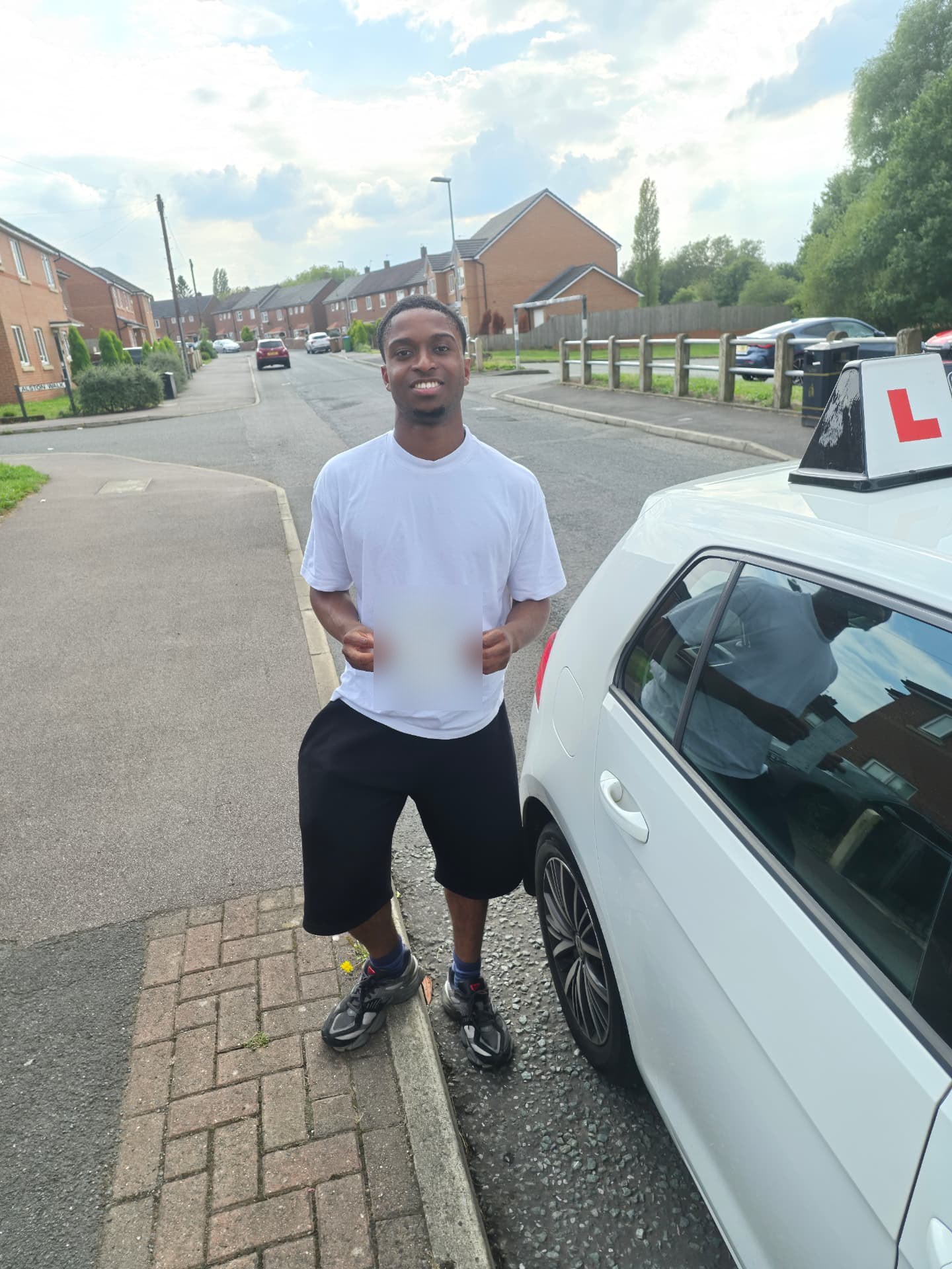 FSK Driving Instructors learner Dindu holding his practical driving test pass certificate next to the learner car in Chadderton
