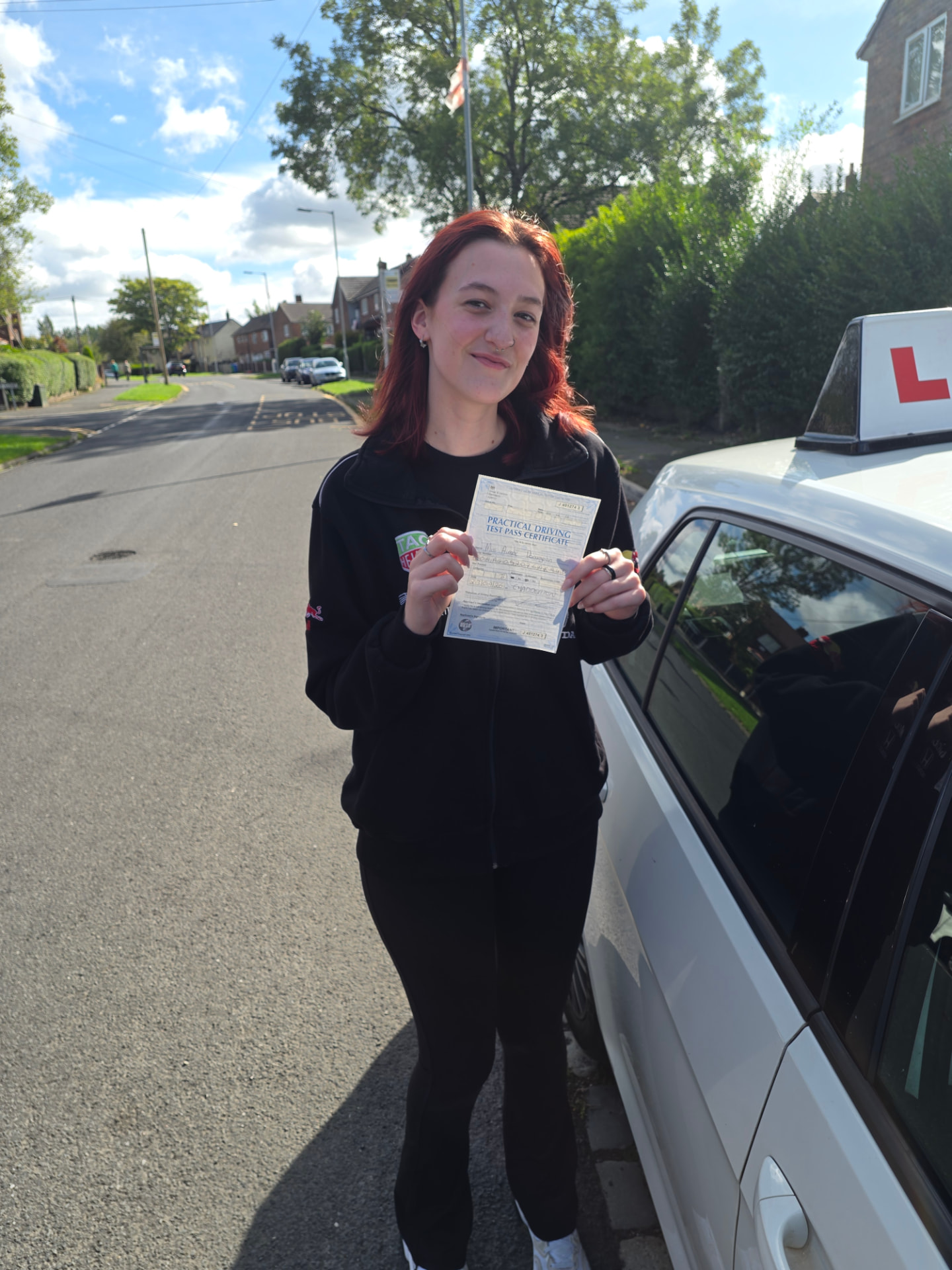 FSK Driving Instructors learner Aimee from Middleton holding her practical driving test pass certificate next to the learner car after passing at Chadderton test centre