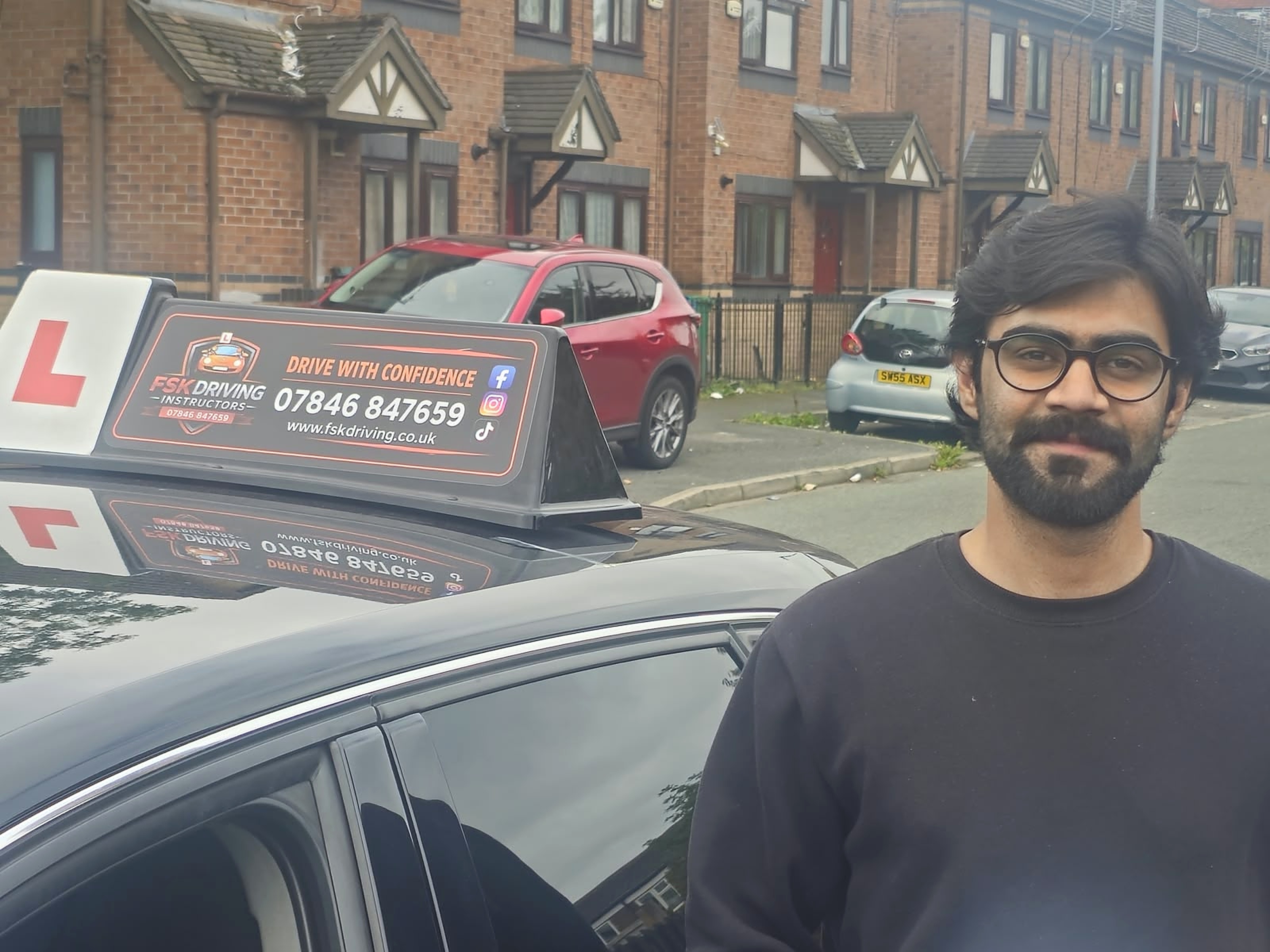 FSK Driving Instructors learner Ibrahim standing next to the FSK learner car after passing his driving test at Cheetham Hill test centre