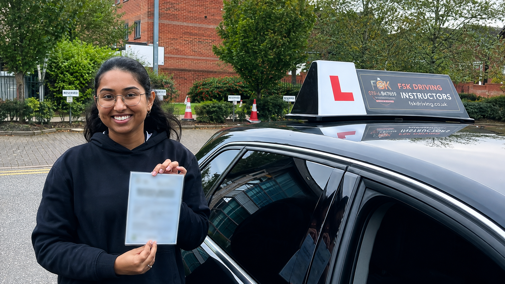 FSK Driving Instructors learner Harsha holding her practical driving test pass certificate next to the learner car at Bury test centre