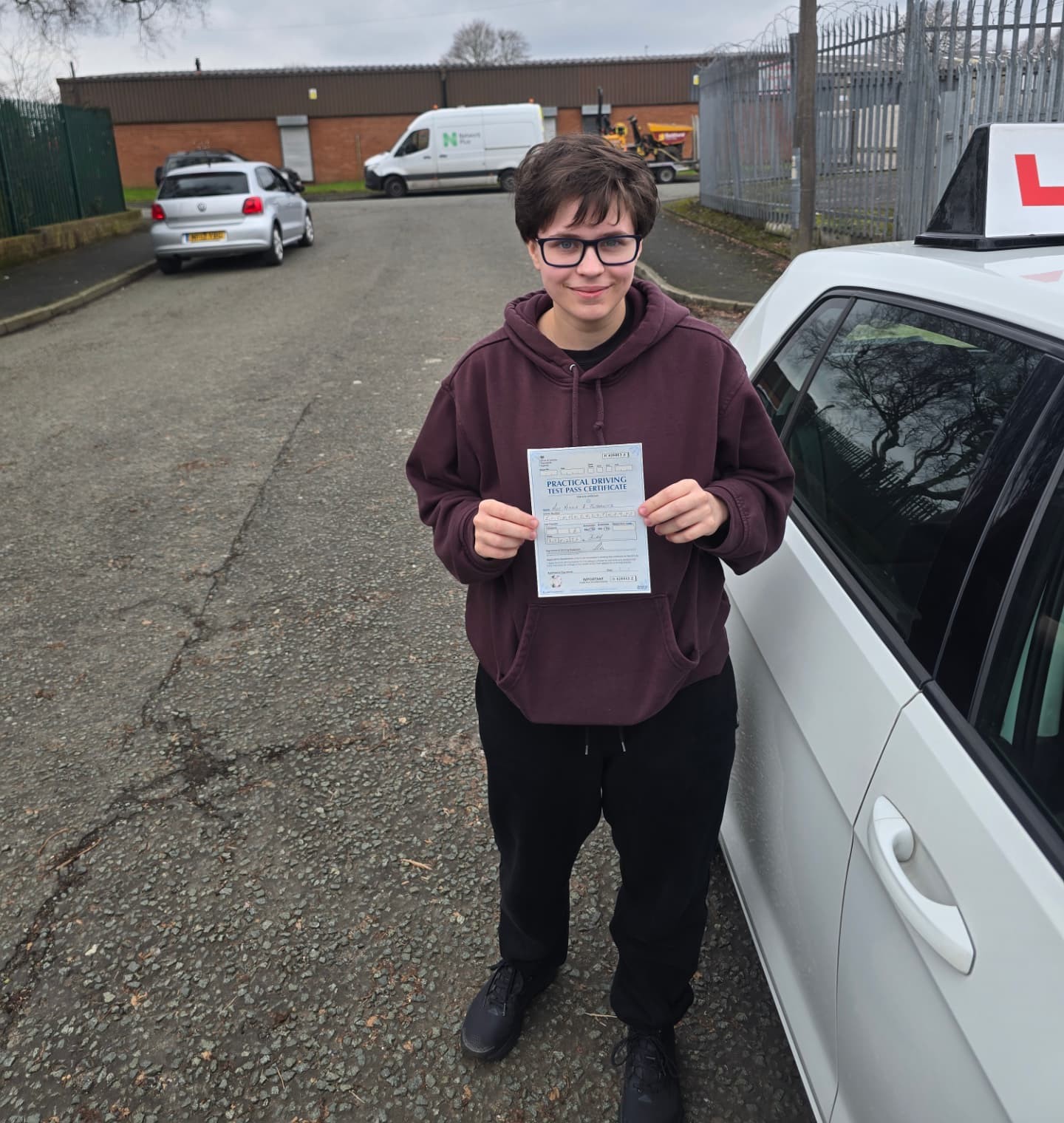 FSK Driving Instructors learner Nikola holding their practical driving test pass certificate next to the learner car in Bury