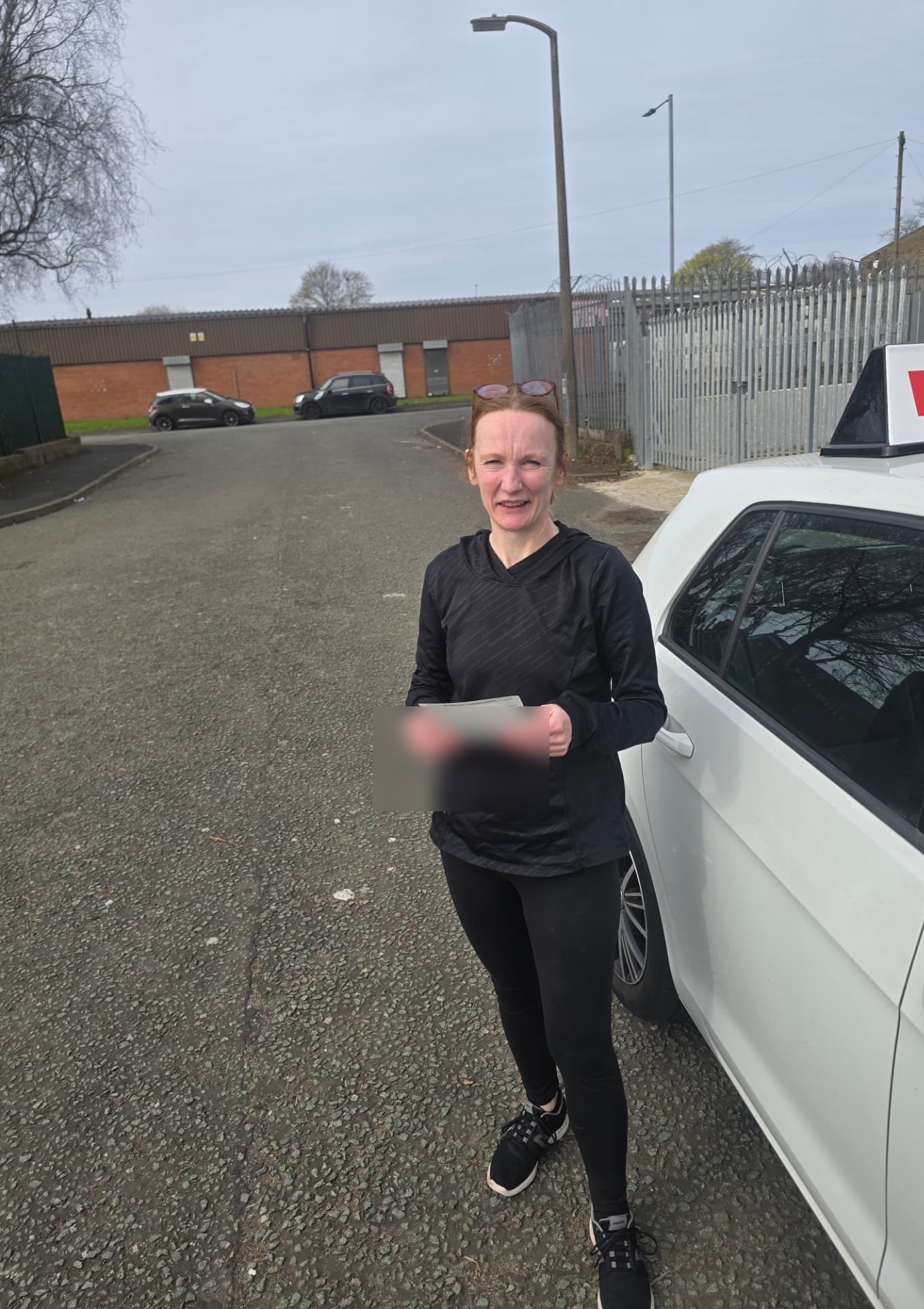 FSK Driving Instructors learner Emma holding her practical driving test pass certificate next to the learner car in Bury